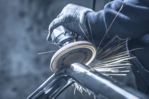 Metal polishing with a hand sander with a polishing disk. Toned image.